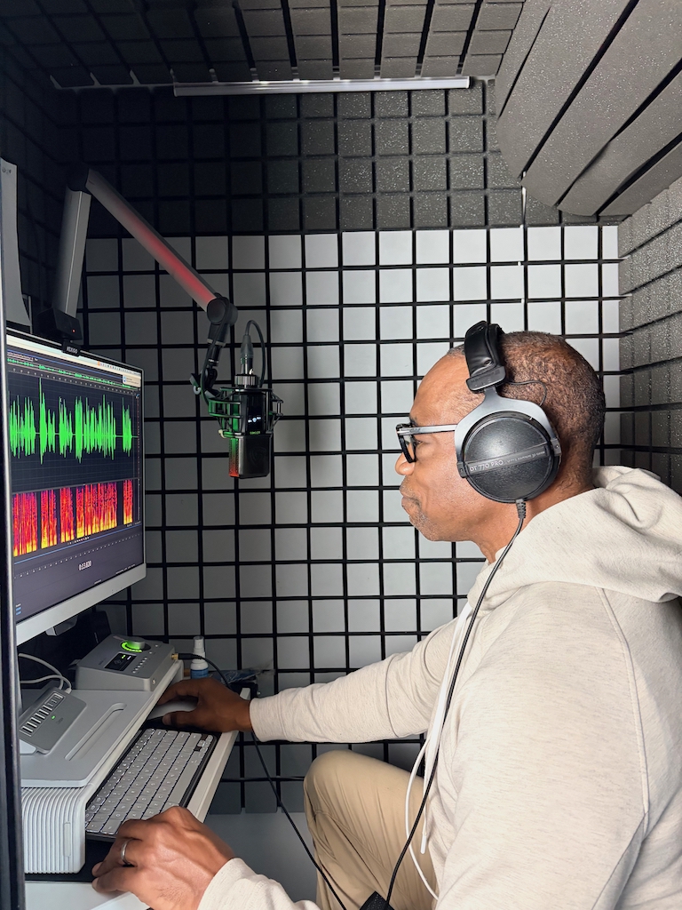 William Marshall Cline in his Voice Over Studio Booth editing Audio on his computer in headphones