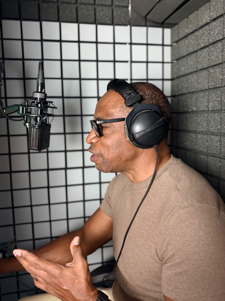 William Marshall Cline, African American voiceover artist and narrator rehearsing a new script in front of the microphone in his Home Recording Studio Booth