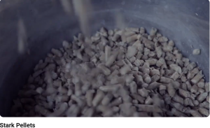 Close up of the Stark Pellets being added to the interior of a metal fireplace/ stove just before being lit., a still from W M Cline Stark Pellets Commercial Voiceover YouTube video
