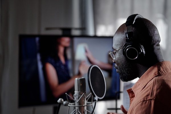 African American man recording podcast wearing headphones in home studio