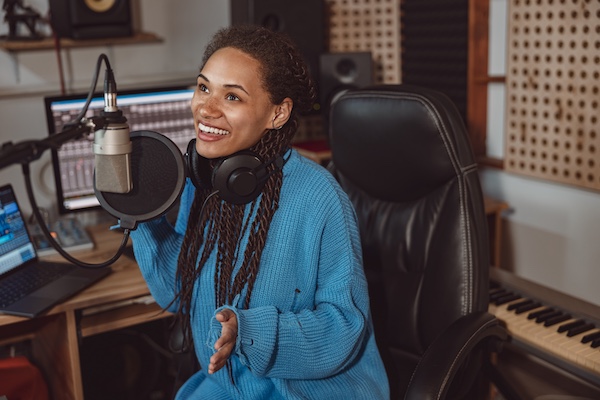 Voice over artist records voiceover job using headphones and talking into microphone